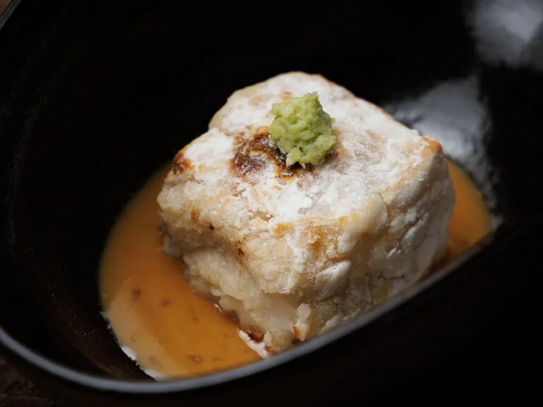 出汁を含んだ揚げ出し豆腐に薬味を添えた小鉢料理
