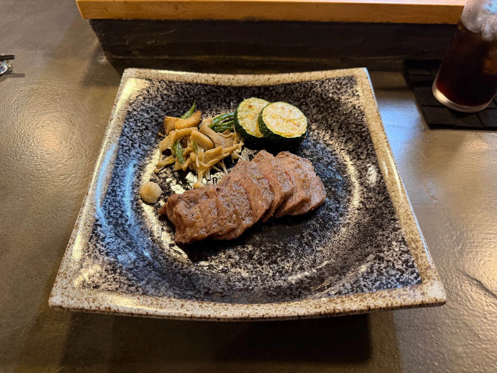 木のカウンター席と料理人の作業台が見える店内
